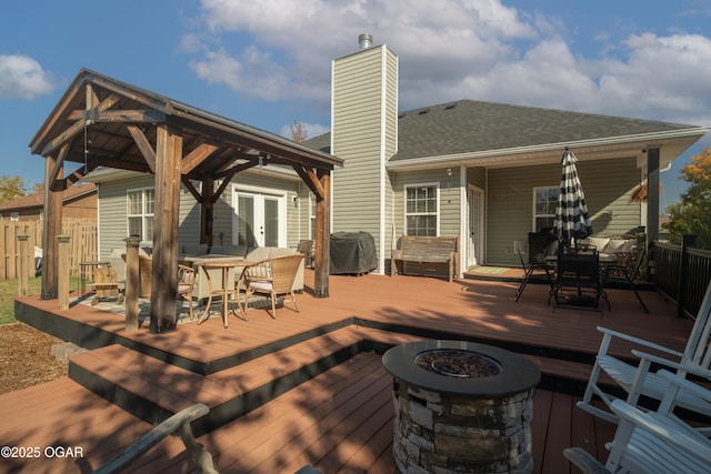 deck featuring outdoor dining space, an outdoor fire pit, fence, and french doors