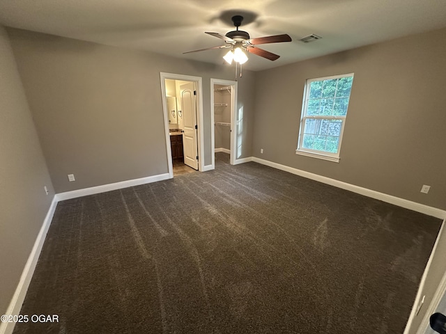 216 N Connor Ave, Joplin, MO 64801 - unfurnished bedroom featuring a walk in closet, baseboards, dark carpet, and connected bathroom