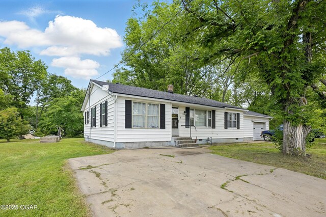 view of front facade with a chimney, a front yard, driveway, and a shingled roof