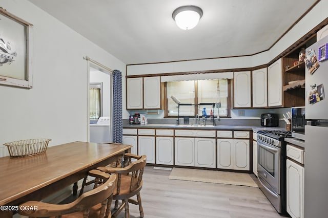kitchen with stainless steel appliances, washer / clothes dryer, light wood-style floors, and a sink