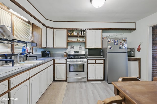 kitchen with stainless steel appliances, a sink, light wood-style flooring, open shelves, and white cabinetry