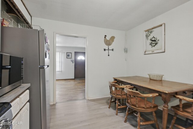 dining space featuring light wood-style floors and baseboards