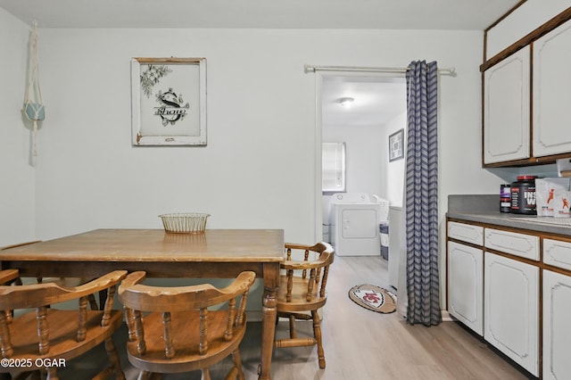 dining space featuring washing machine and clothes dryer and light wood finished floors