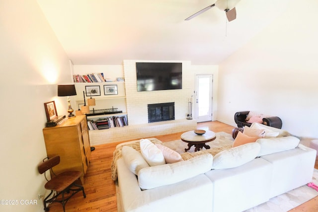 608 Sycamore Ln, Pittsburg, KS 66762 - living room featuring wood finished floors, lofted ceiling, a brick fireplace, and a ceiling fan