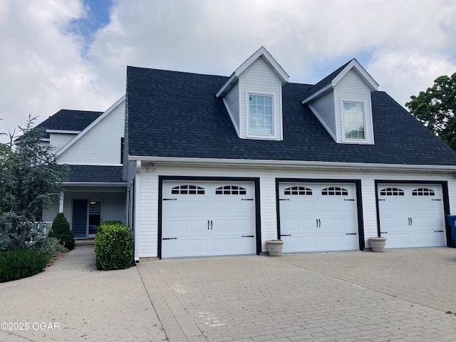view of front facade featuring driveway, an attached garage, and a shingled roof