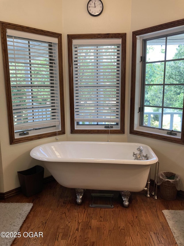 full bathroom with wood finished floors, baseboards, and a freestanding bath