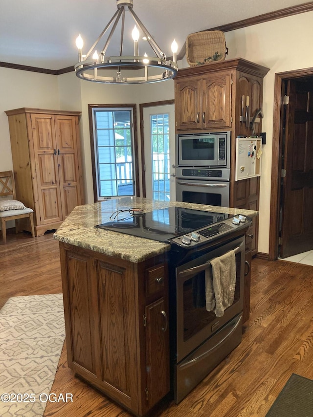 kitchen featuring appliances with stainless steel finishes, a chandelier, crown molding, dark wood-type flooring, and light stone counters