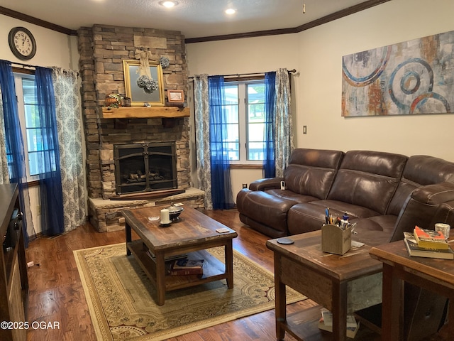 living room featuring ornamental molding, a stone fireplace, wood finished floors, and recessed lighting