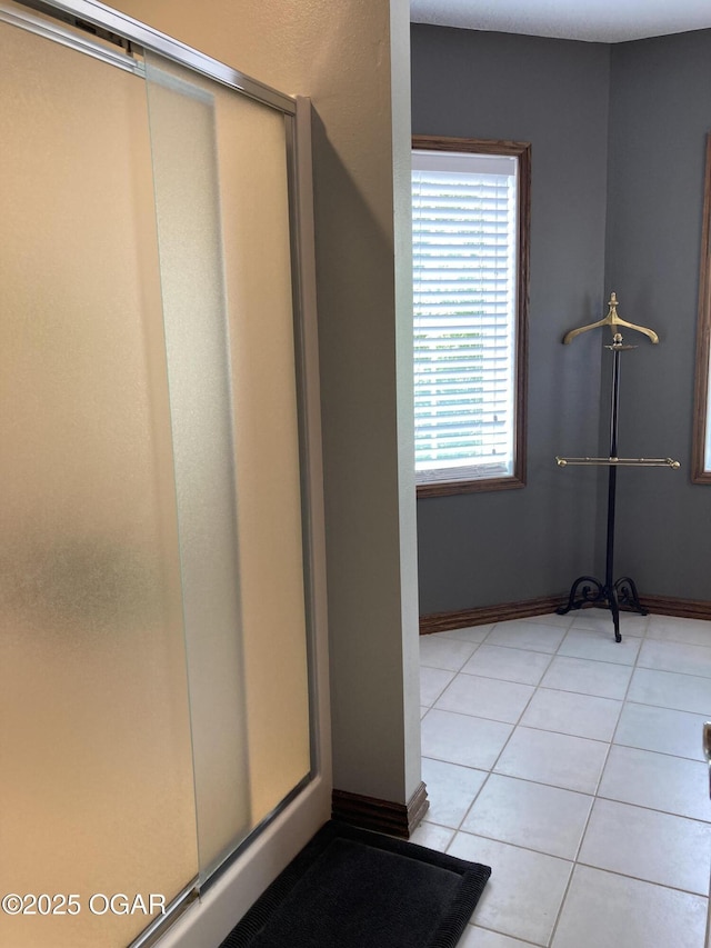 bathroom featuring tile patterned floors, a shower with door, and baseboards