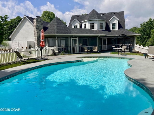 view of pool with a sunroom, a patio, and fence