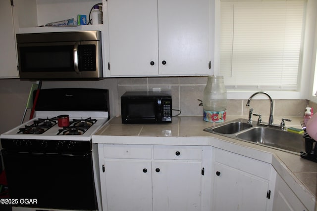 504 E Jackson St, Pittsburg, KS 66762 - kitchen with range with gas stovetop, stainless steel microwave, black microwave, a sink, and white cabinetry