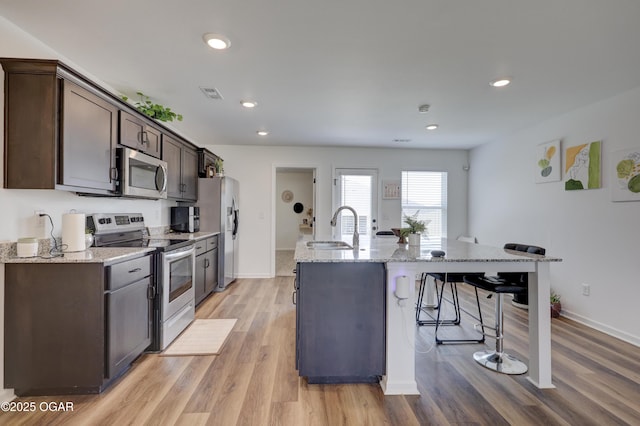 414 Eagle Edge Ave, Duenweg, MO 64841 - kitchen featuring stainless steel appliances, a breakfast bar area, a sink, dark brown cabinets, and a kitchen island with sink