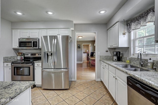 1912 N Duquesne Rd, Joplin, MO 64801 - kitchen featuring stainless steel appliances, a sink, white cabinetry, light stone countertops, and baseboards
