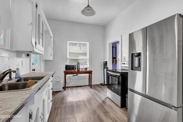 1815 S Empire Ave, Joplin, MO 64801 - kitchen featuring appliances with stainless steel finishes, a sink, light wood-type flooring, and white cabinetry