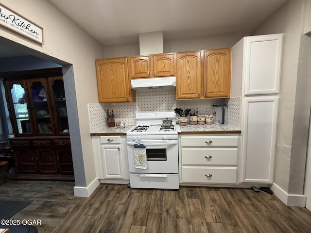 304 Market St, Wentworth, MO 64873 - kitchen with white gas range oven, under cabinet range hood, light countertops, backsplash, and dark wood-type flooring