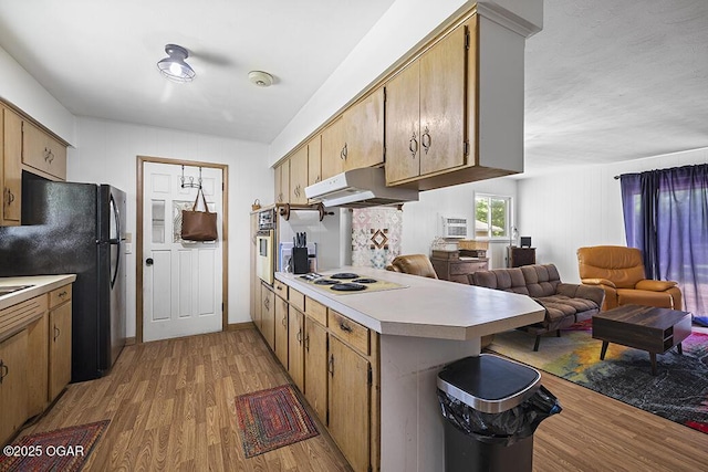 103 E Mockingbird Ln, Crane, MO 65633 - kitchen with under cabinet range hood, white electric cooktop, wood finished floors, oven, and light countertops