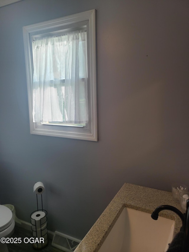 511 3rd St, Mccune, KS 66753 - bathroom featuring toilet, baseboards, and a sink