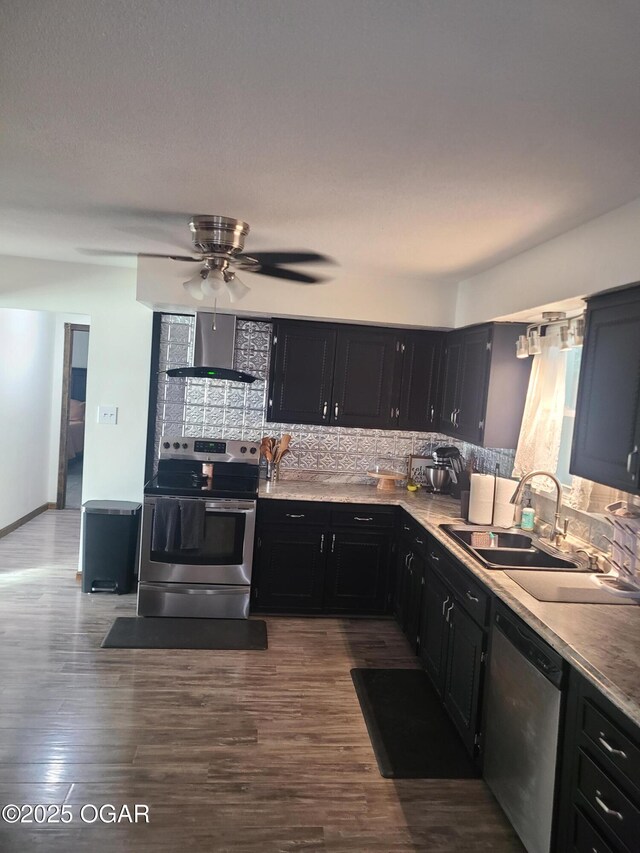 511 3rd St, Mccune, KS 66753 - kitchen featuring appliances with stainless steel finishes, wall chimney range hood, a sink, dark cabinets, and decorative backsplash