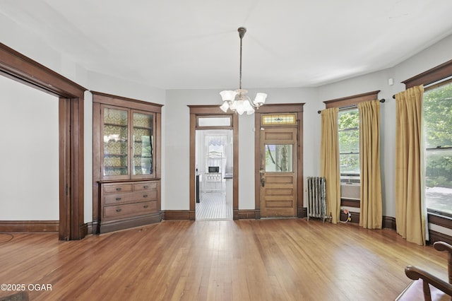 524 W 5th St, Joplin, MO 64801 - foyer with radiator heating unit, light wood-type flooring, a chandelier, and baseboards