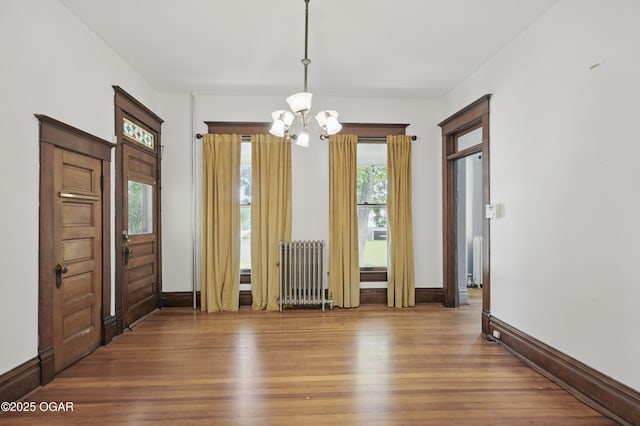 524 W 5th St, Joplin, MO 64801 - unfurnished dining area featuring radiator heating unit, a chandelier, wood finished floors, and healthy amount of natural light