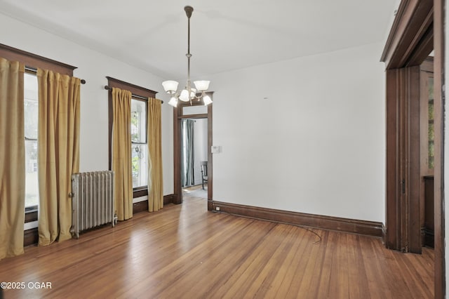 524 W 5th St, Joplin, MO 64801 - empty room with radiator heating unit, a chandelier, baseboards, and wood finished floors