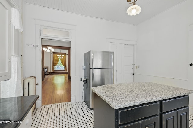 524 W 5th St, Joplin, MO 64801 - kitchen with freestanding refrigerator, light floors, dark cabinetry, a kitchen island, and light stone countertops