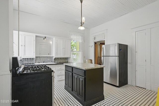 524 W 5th St, Joplin, MO 64801 - kitchen with freestanding refrigerator, black range with gas cooktop, light floors, white cabinetry, and decorative backsplash