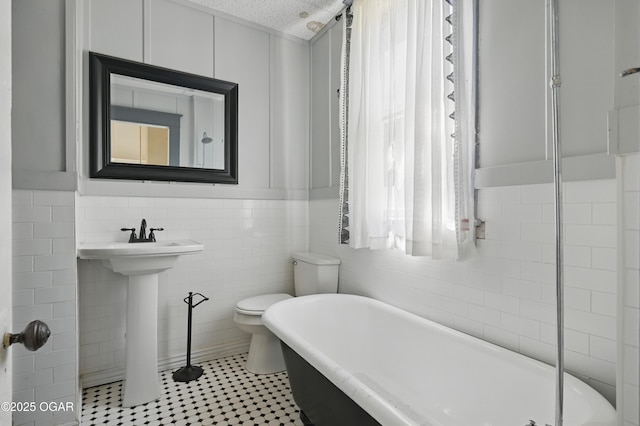 524 W 5th St, Joplin, MO 64801 - bathroom featuring a soaking tub, tile walls, toilet, a sink, and tile patterned flooring