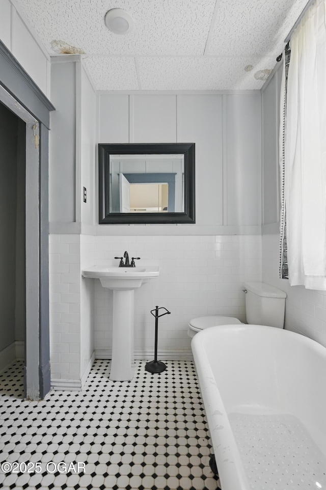 524 W 5th St, Joplin, MO 64801 - full bathroom with a soaking tub, toilet, tile patterned flooring, a sink, and tile walls