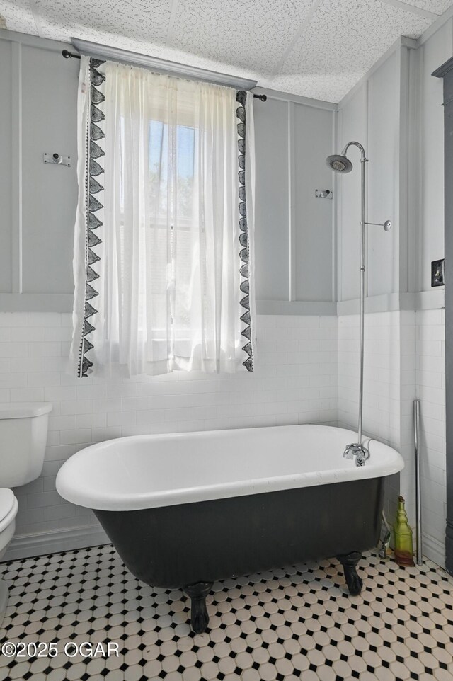 524 W 5th St, Joplin, MO 64801 - full bathroom featuring tile walls, toilet, a freestanding bath, tile patterned flooring, and wainscoting