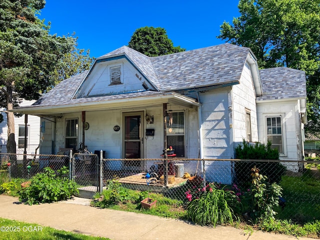 1017 E Broadway St, Joplin, MO 64801 - bungalow-style home with a gate, a porch, a fenced front yard, and stone siding