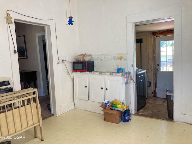 1017 E Broadway St, Joplin, MO 64801 - kitchen with white cabinetry, heating unit, light countertops, and washer / dryer
