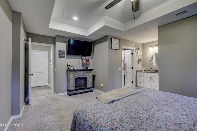 2615 E Xenia St, Joplin, MO 64801 - bedroom featuring light colored carpet, baseboards, a stone fireplace, a tray ceiling, and connected bathroom