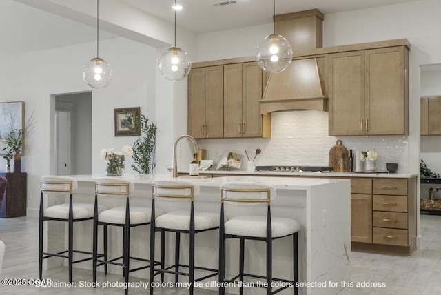 1713 E White Oak St, Joplin, MO 64801 - kitchen with premium range hood, black stovetop, a kitchen island with sink, backsplash, and decorative light fixtures
