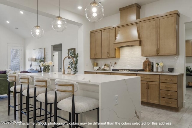 1713 E White Oak St, Joplin, MO 64801 - kitchen with stovetop, decorative backsplash, light stone counters, a kitchen island with sink, and premium range hood