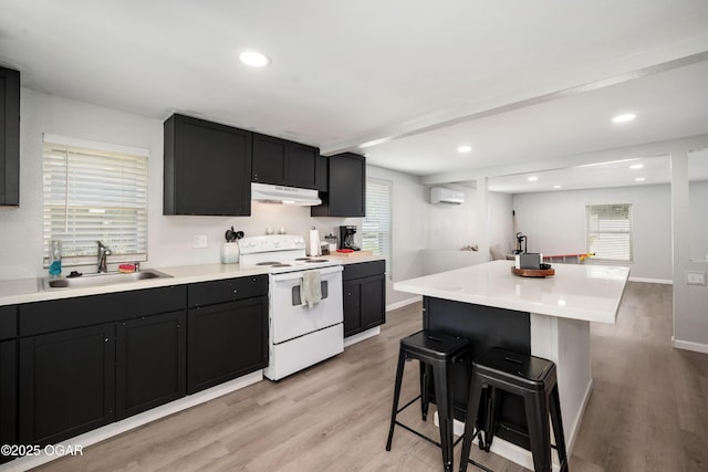 201 S Tom, Webb City, MO 64870 - kitchen featuring white electric stove, a sink, under cabinet range hood, a kitchen breakfast bar, and light wood finished floors