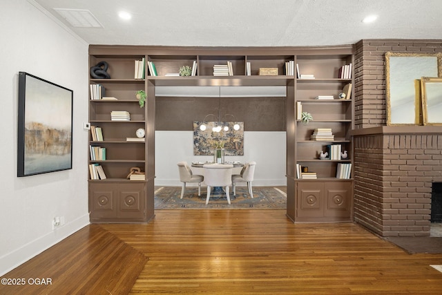 2716 E 14th St, Joplin, MO 64801 - home office featuring wood finished floors, baseboards, a brick fireplace, built in features, and a chandelier