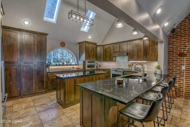 4 Emerald Dr, Joplin, MO 64804 - kitchen featuring a skylight, a sink, vaulted ceiling, appliances with stainless steel finishes, and dark stone counters