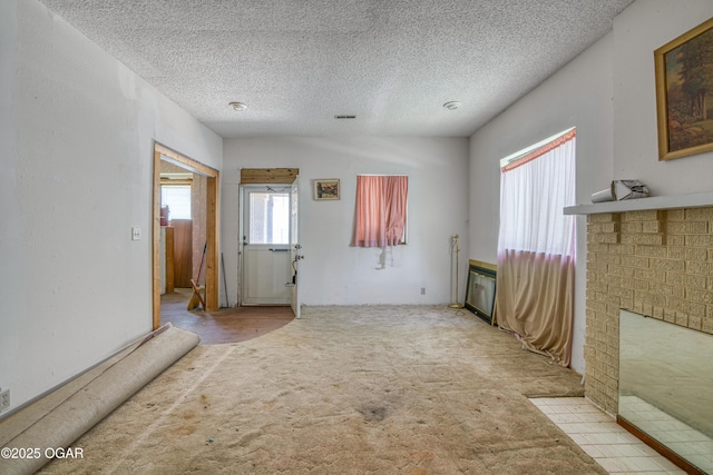 219 N Moffet Ave, Joplin, MO 64801 - empty room with carpet, a textured ceiling, and a fireplace with flush hearth