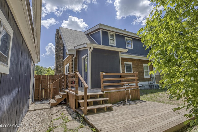 3219 Hughes Ave, Parsons, KS 67357 - back of property with a deck, a shingled roof, central AC unit, and stone siding