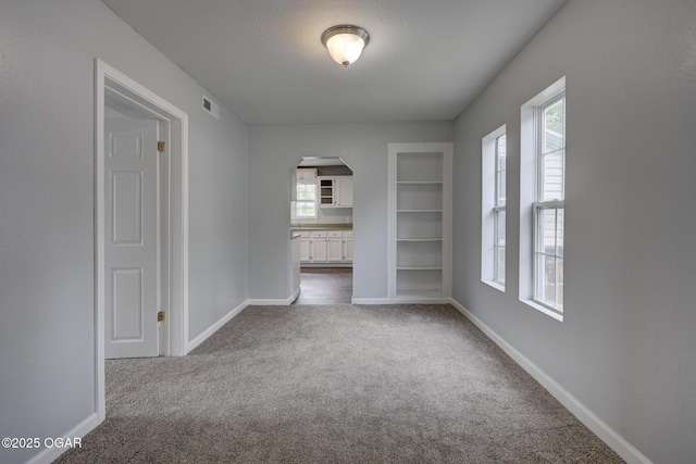 109 N Main St, Alba, MO 64830 - unfurnished room featuring arched walkways, carpet flooring, built in features, and baseboards