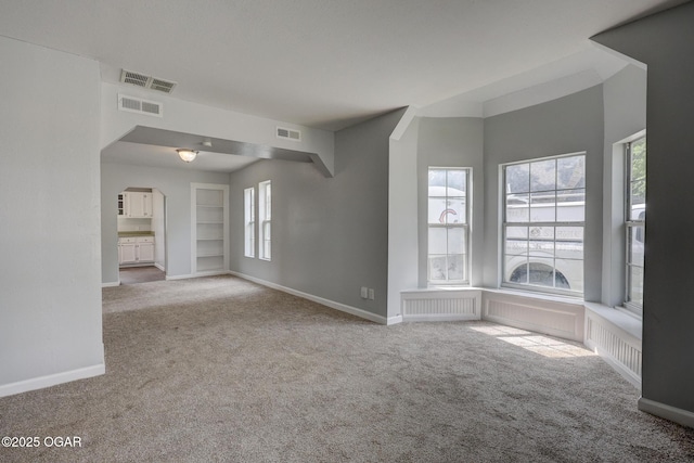 109 N Main St, Alba, MO 64830 - unfurnished living room with carpet, baseboards, arched walkways, and built in shelves