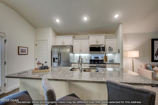 1619 Sedge St, Joplin, MO 64801 - kitchen with stainless steel appliances, a sink, white cabinets, a kitchen breakfast bar, and light stone counters