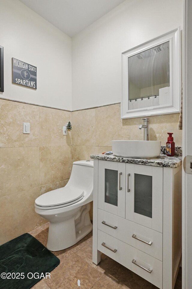 5594 Riverside Dr, Joplin, MO 64804 - half bath featuring tile walls, toilet, vanity, tile patterned flooring, and a wainscoted wall