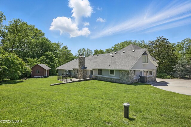 5594 Riverside Dr, Joplin, MO 64804 - back of house with central AC unit, a chimney, stone siding, and a yard