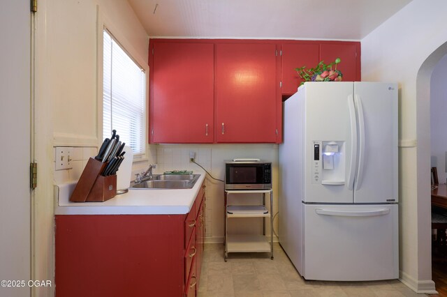 430 N Jackson Ave, Joplin, MO 64801 - kitchen with white fridge with ice dispenser, red cabinetry, stainless steel microwave, a sink, and arched walkways