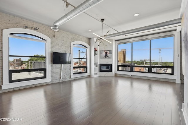 214 E 4th St Unit 402, Joplin, MO 64801 - unfurnished living room with healthy amount of natural light, a glass covered fireplace, a chandelier, wood finished floors, and recessed lighting
