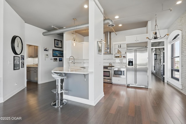 214 E 4th St Unit 402, Joplin, MO 64801 - kitchen featuring built in appliances, open shelves, wall chimney range hood, a breakfast bar, and decorative backsplash