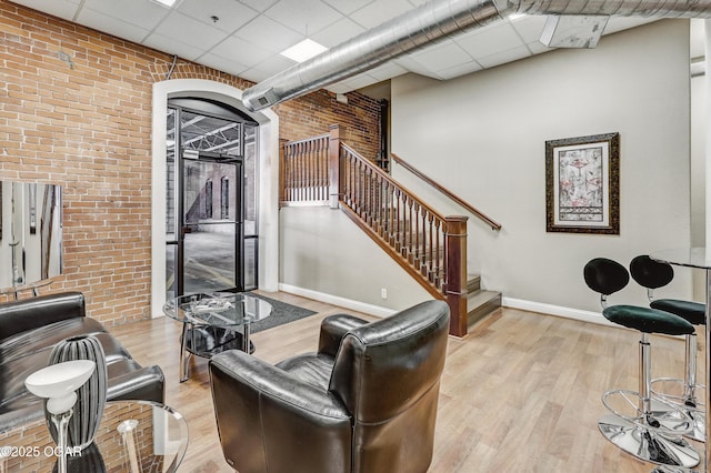 214 E 4th St Unit 402, Joplin, MO 64801 - living area featuring a drop ceiling, baseboards, light wood-type flooring, brick wall, and stairway
