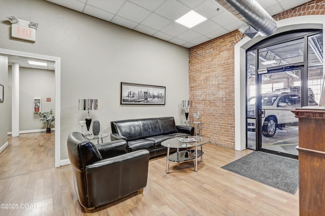 214 E 4th St Unit 402, Joplin, MO 64801 - living room with light wood finished floors, a drop ceiling, baseboards, and brick wall